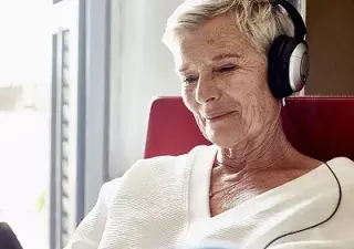 Una persona mayor escuchando por unos auriculares (Fuente: Oticon)