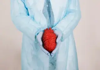 Manos de cirujanos sujetando un corazón
