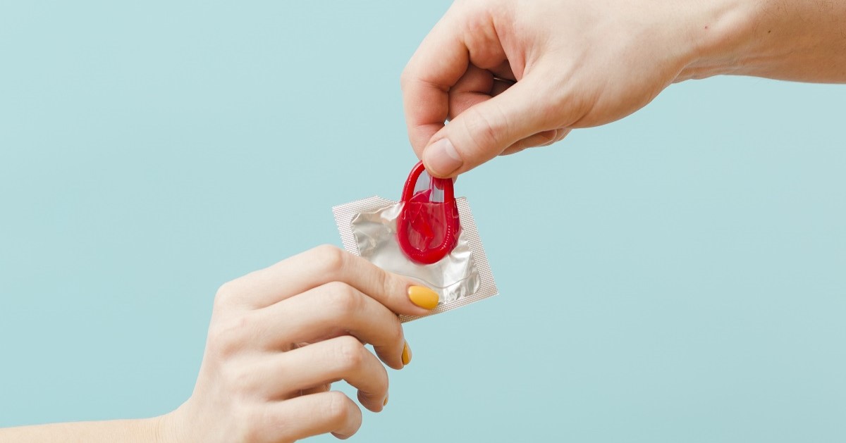 dos personas sostienen un condon. La imágen representa las Infecciones de transmisión sexual (ITS)