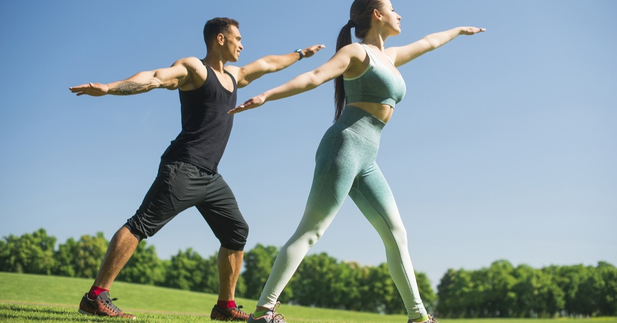 hombre y mujer practicando una actividad física como el yoga en una pradera
