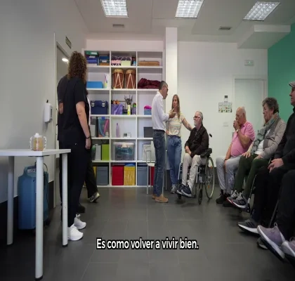 Personas diversas en una sala, aparecen sentadas.