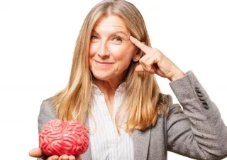 mujer llevando un dedo a la sien y con la otra mano sosteniendo un cerebro de juguete
